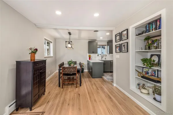 a living room with stainless steel appliances furniture a dining table and a bookshelf