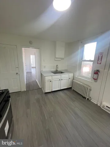 a view of an empty room with wooden floor and windows