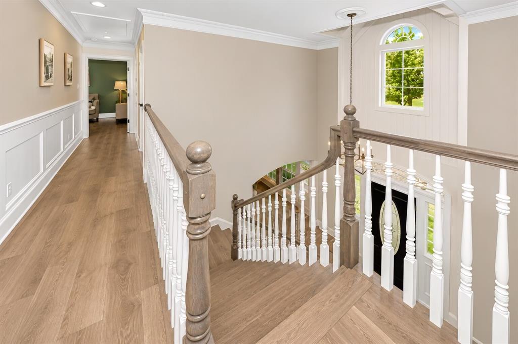 3817 Ganzer Road West Denton, TX 76207 - Photo 22 of 40 Upstairs opens into a bright, easy-flow landing where natural light pours through the arched window and spills across the wood floors. The open railing keeps the space feeling connected to the foyer below, while the hallway leads quietly into the primary suite and secondary bedrooms. It’s one of those spots in the home that feels calm — a soft pause between spaces — and gives the upstairs a modern farmhouse openness that buyers love.