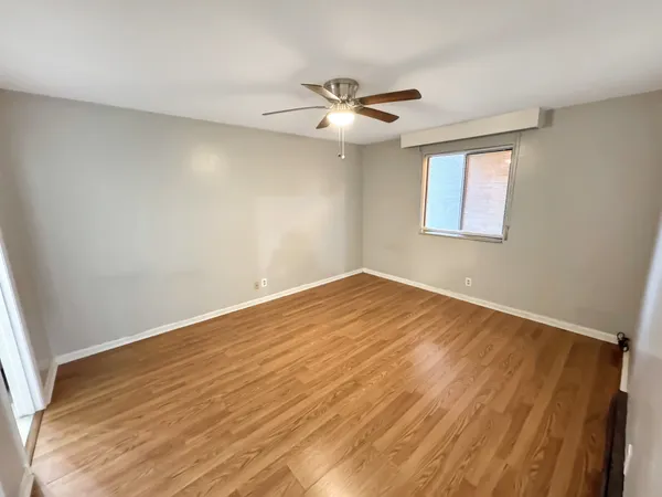 a view of empty room with wooden floor and fan