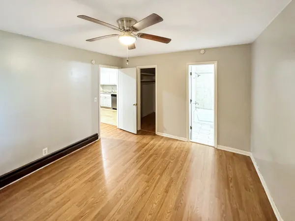 an empty room with wooden floor and ceiling fan
