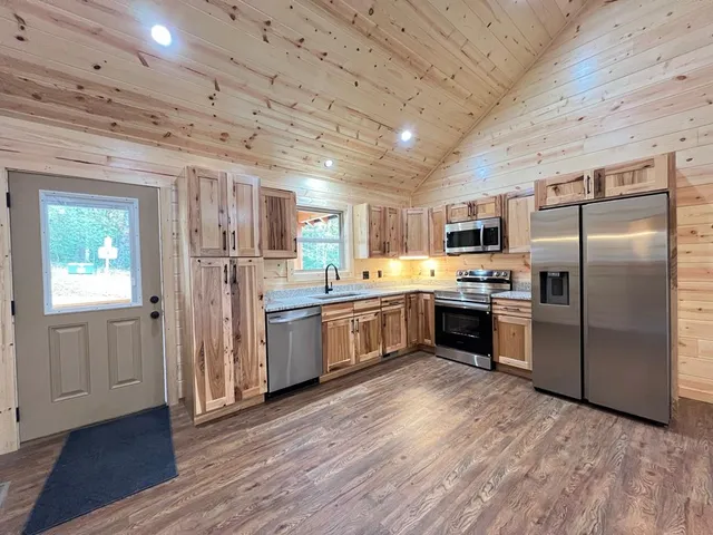 a kitchen with stainless steel appliances granite countertop a refrigerator oven a sink dishwasher and white cabinets with wooden floor