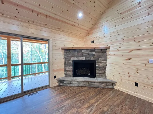 a view of an empty room with wooden floor and a fireplace