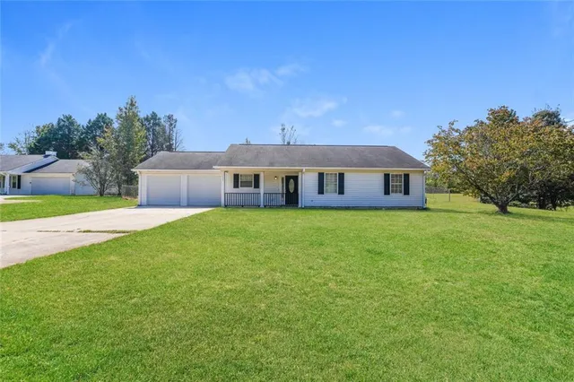 a front view of house with yard and trees in the background