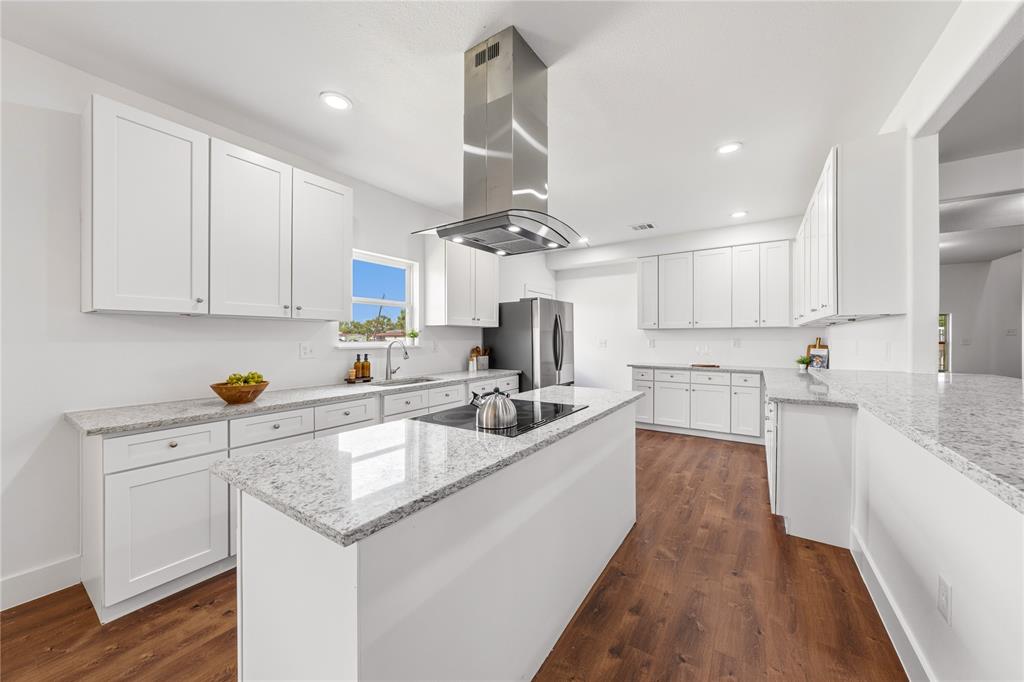 1128 Newton Road Ferris, TX 75125 - Photo 9 of 28 Modern kitchen featuring an expansive center island with an integrated cooktop and stainless steel range hood