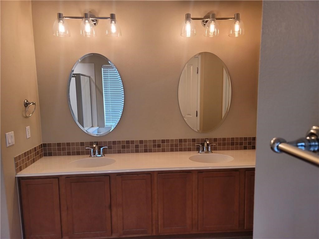 208 Hummingbird Lane Leander, TX 78641 - Photo 14 of 25 Two individual vanity mirrors with overhead lighting illuminate this bathroom's double sink area.