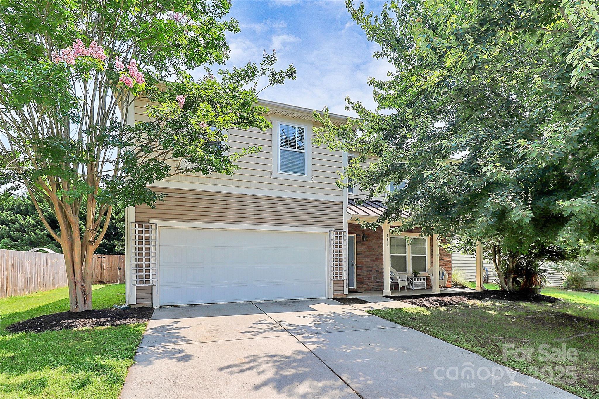 a front view of a house with a garden and trees