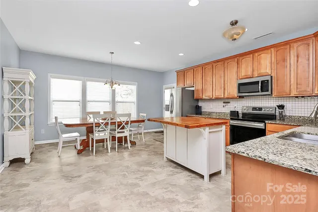 a kitchen with stainless steel appliances granite countertop a stove top oven a sink dishwasher a dining table and chairs with wooden floor