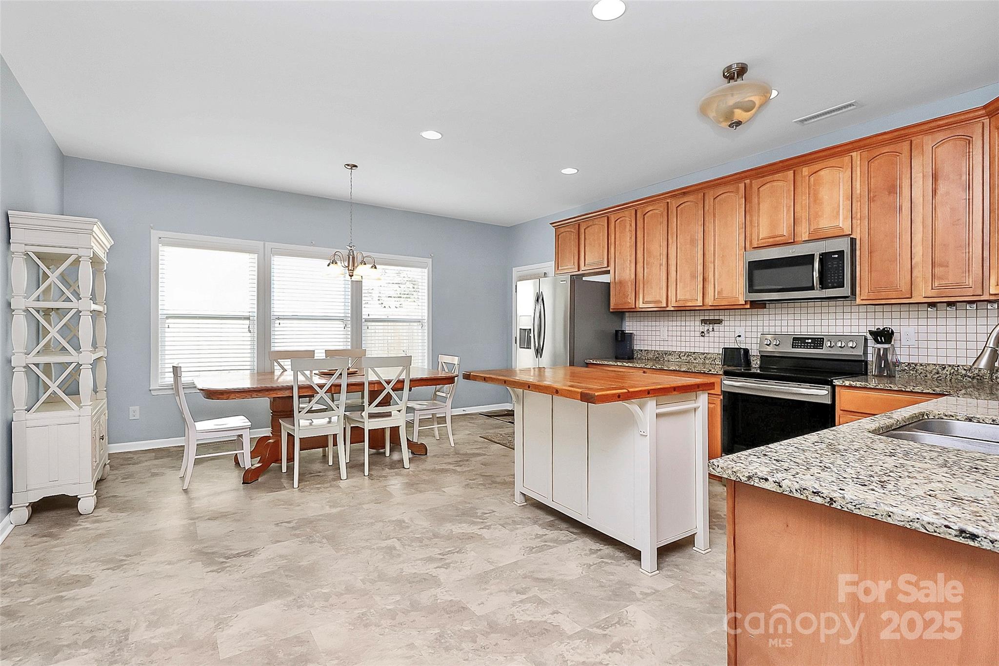 1817 Tradd Avenue Clover, SC 29710 - Photo 20 of 42 a kitchen with kitchen island granite countertop wooden cabinets a stove a sink a dining table and chairs