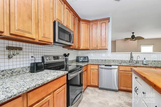 a kitchen with granite countertop a refrigerator stove top oven and sink