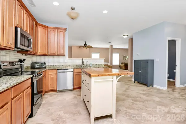 a large kitchen with granite countertop a stove top oven a sink a window and stainless steel appliances