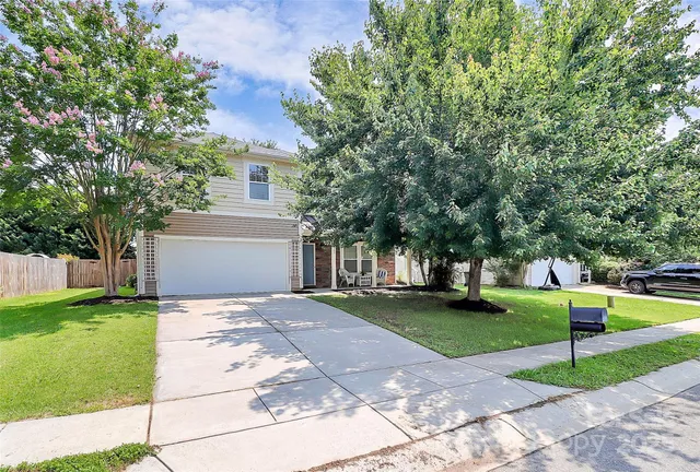 a front view of a house with a yard and trees