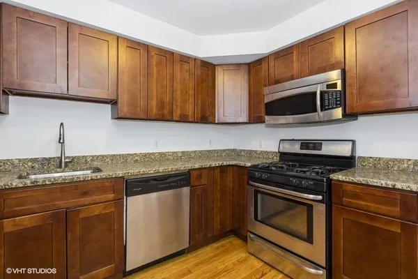 a kitchen with granite countertop cabinets stainless steel appliances and a sink