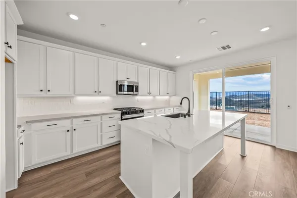 a open kitchen with white cabinets stove and wooden floor