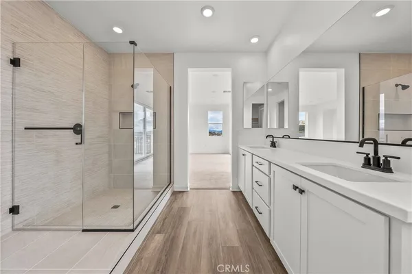 a large white bathroom with a double vanity sink a large mirror and shower