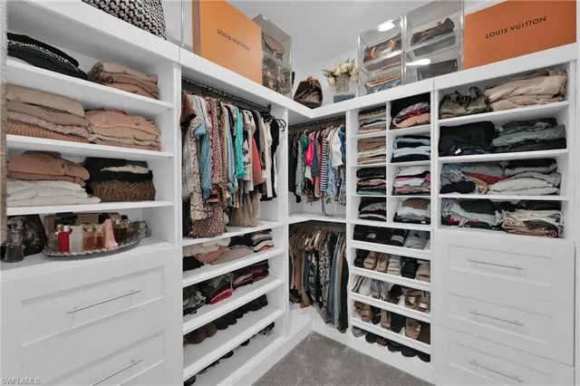 a view of walk in closet with clothes and shoes