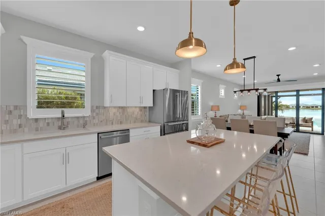 a kitchen with stainless steel appliances granite countertop a sink a stove a dining table and chairs