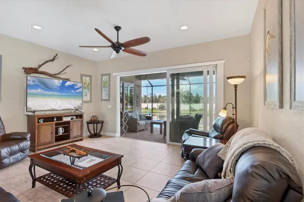 a living room with furniture a flat screen tv and a floor to ceiling window