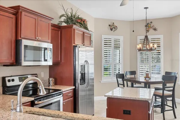 a kitchen with stainless steel appliances granite countertop a stove a refrigerator a kitchen island a dining table and chairs with wooden floor