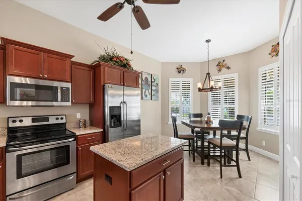 a kitchen with stainless steel appliances granite countertop a stove a refrigerator a kitchen island a dining table and chairs with wooden floor