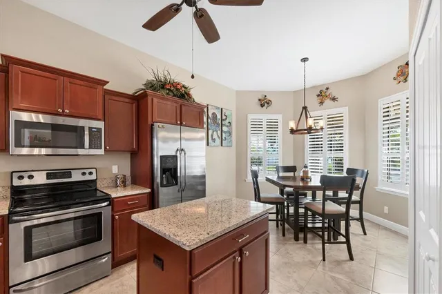 a kitchen with stainless steel appliances granite countertop a stove a refrigerator a kitchen island a dining table and chairs with wooden floor