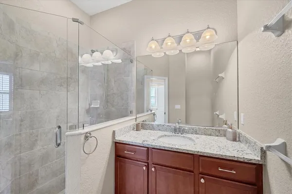 a bathroom with a granite countertop sink a mirror and a shower