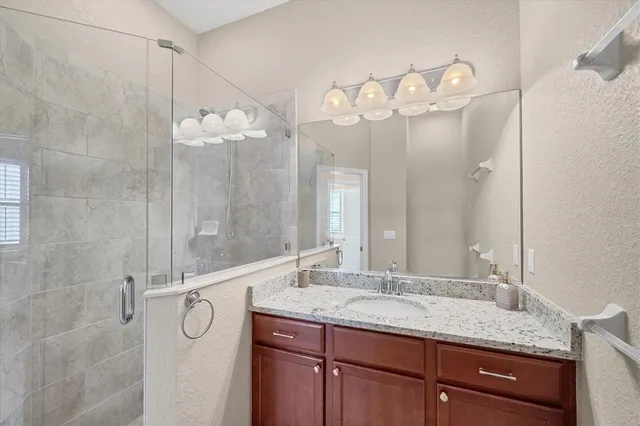 a bathroom with a granite countertop sink a mirror and a shower