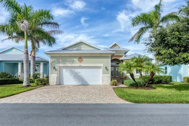 a front view of a house with a garden and palm trees