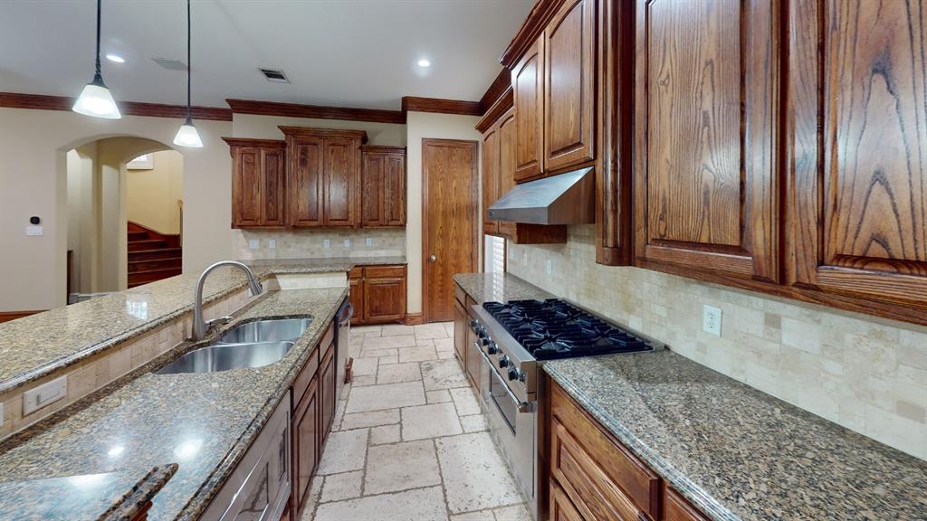 4516 Gilbert Avenue Dallas, TX 75219 - Photo 4 of 28 Gourmet kitchen featuring extensive wood cabinetry, granite countertops, stainless steel appliances, a gas cooktop with a professional-grade hood, and neutral-toned tile flooring