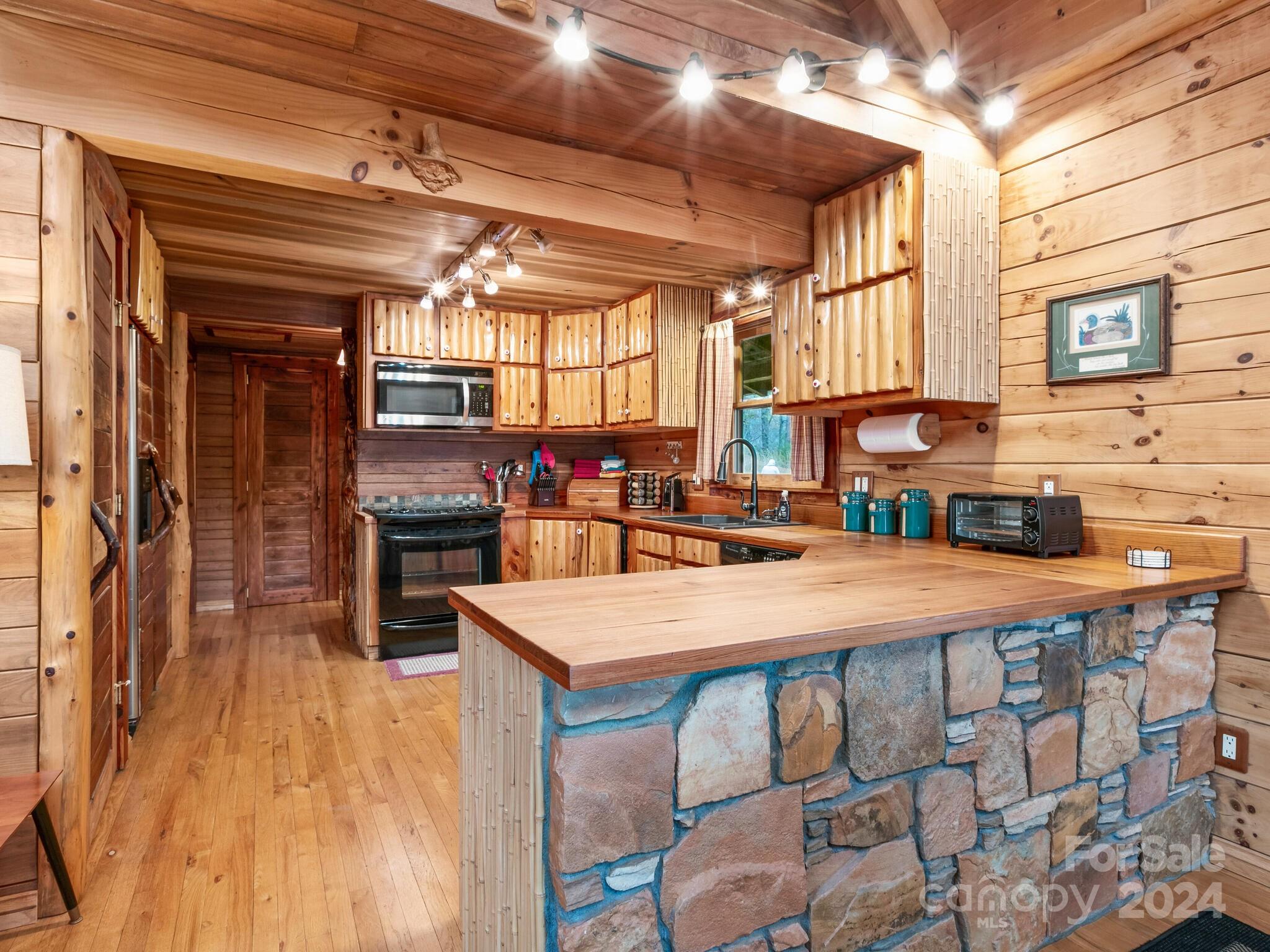 354 Nelons Road Mill Spring, NC 28756 - Photo 15 of 32 a room with stainless steel appliances kitchen island granite countertop a table chairs in it and wooden floor