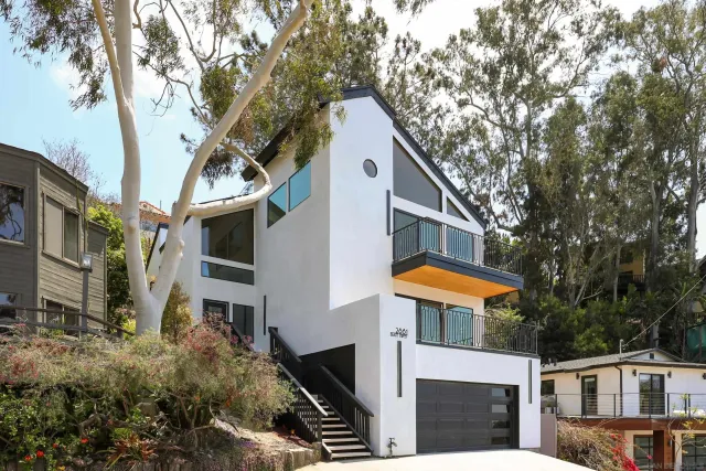 a front view of a house with large trees