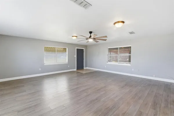 an empty room with wooden floor chandelier and windows