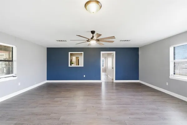 a view of an empty room with wooden floor and a window