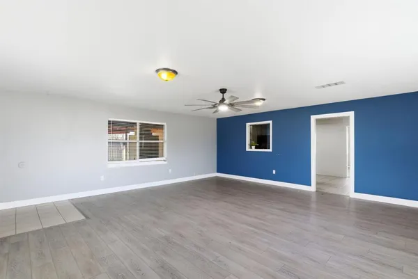 a view of an empty room with wooden floor and window