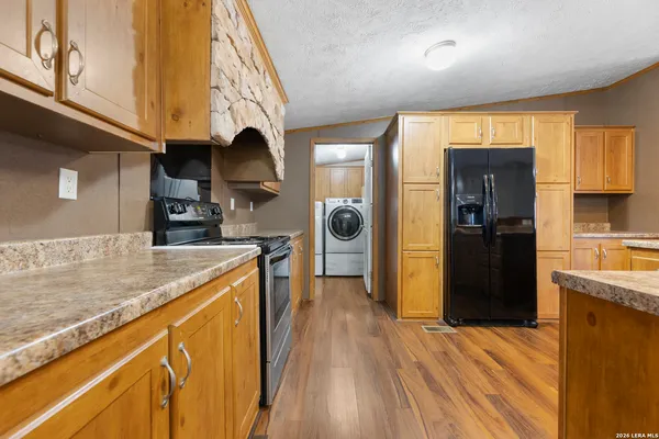 a kitchen with stainless steel appliances granite countertop a refrigerator a sink dishwasher and wooden cabinets with wooden floor
