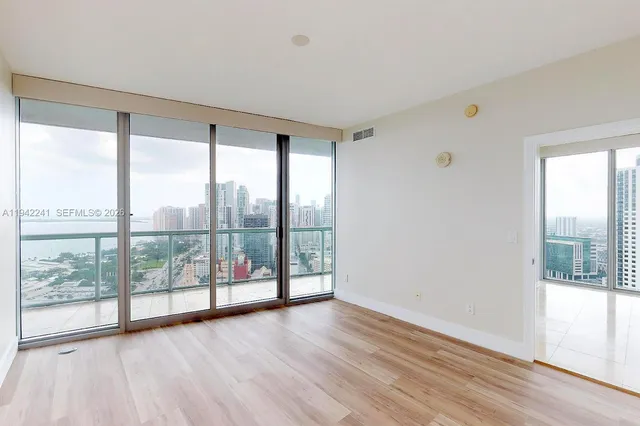 an empty room with wooden floor and windows with view