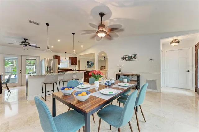 a dining room with wooden floor a chandelier fan a wooden table and chairs