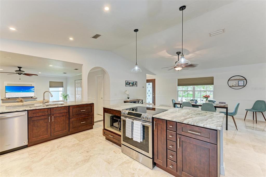 6715 12th Avenue Northwest Bradenton, FL 34209 - Photo 9 of 43 a kitchen with stainless steel appliances granite countertop stove a sink dishwasher and white cabinets with wooden floor