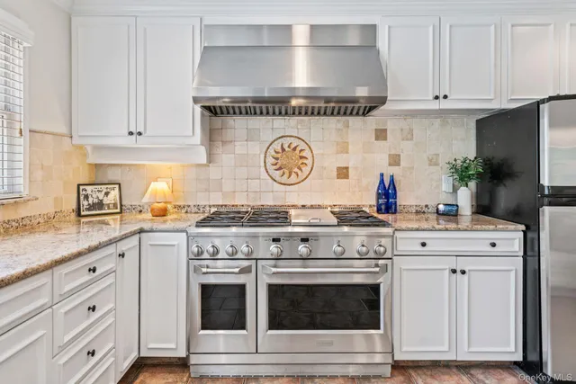 a kitchen with granite countertop white cabinets and stainless steel appliances