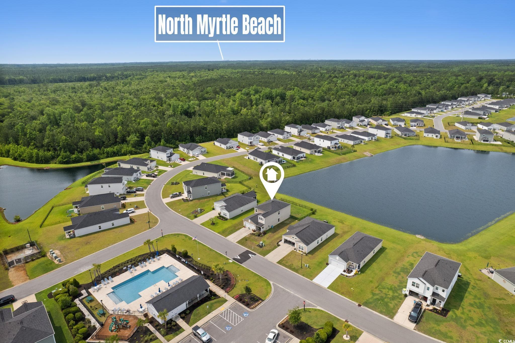 196 Cypress Tree Loop Longs, SC 29568 - Photo 36 of 40 Aerial perspective of suburban area with a heavily wooded area, a pool, and a large body of water