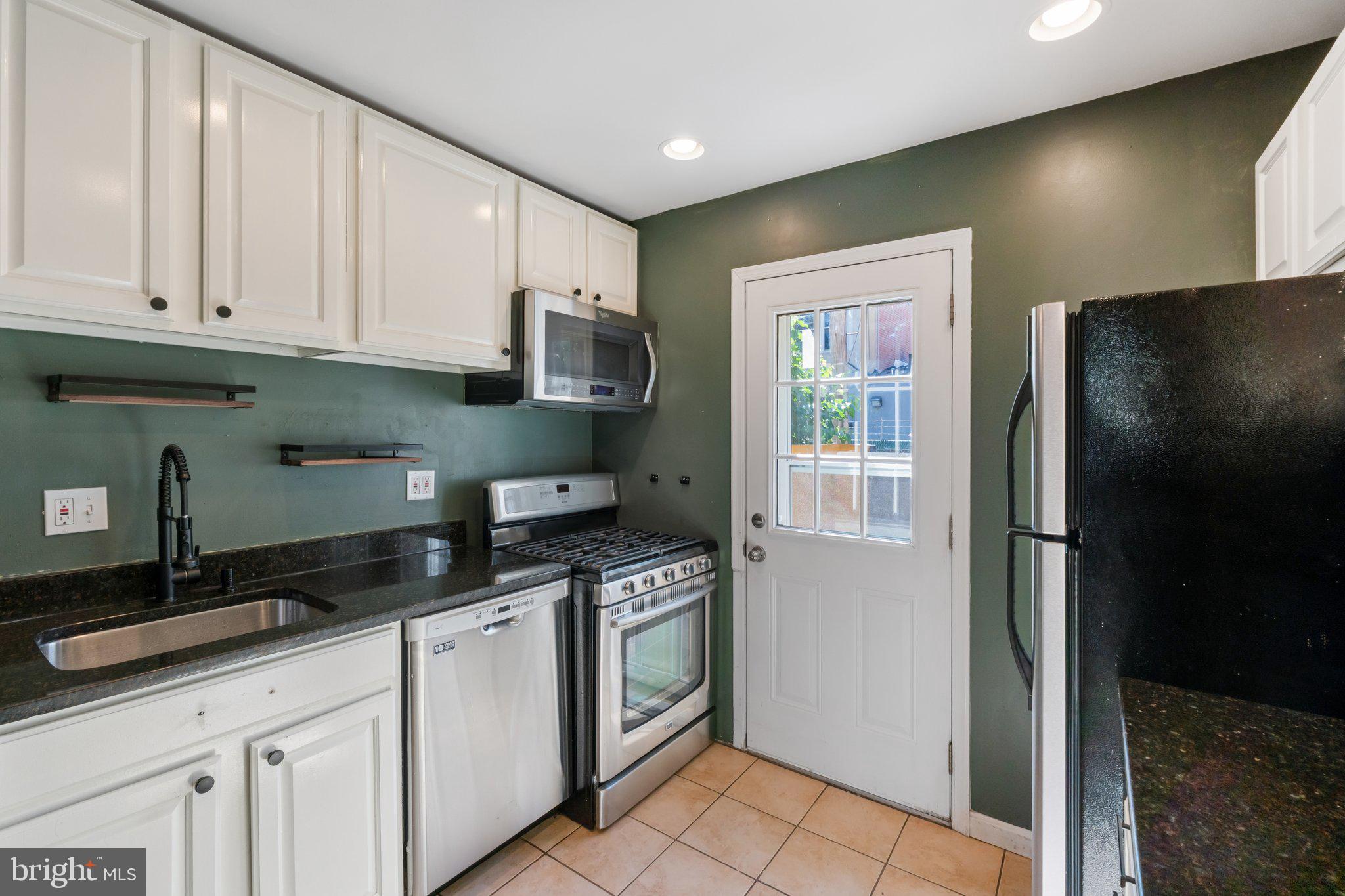 1227 Wylie Street Northeast Washington, DC 20002 - Photo 5 of 20 a kitchen with granite countertop a refrigerator a sink and white cabinets