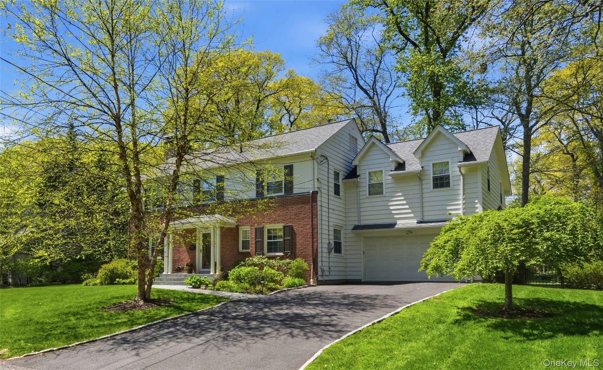 136 Devonshire Road Larchmont, NY 10538 - Photo 2 of 34 a view of a big yard in front of a brick house with plants and large tree