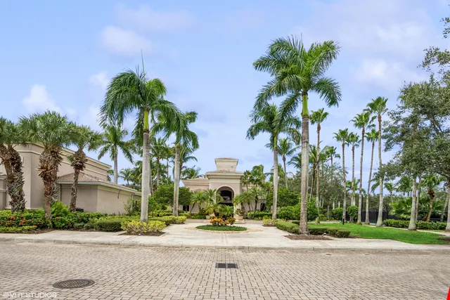 front view of a house with a yard and palm trees