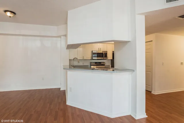 a view of kitchen with stainless steel appliances wooden floor and chair