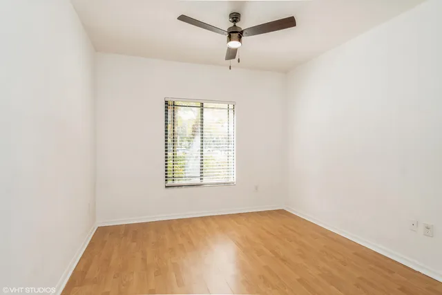 an empty room with a window and a ceiling fan