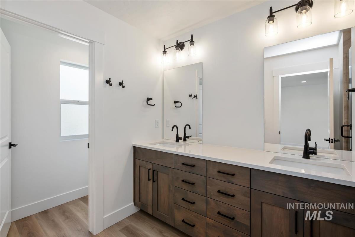 768 South Calhoun Lane Star, ID 83669 - Photo 23 of 36 Bathroom featuring a double vanity with wood-finish cabinetry, white countertops, and dual undermount sinks with matte black faucets