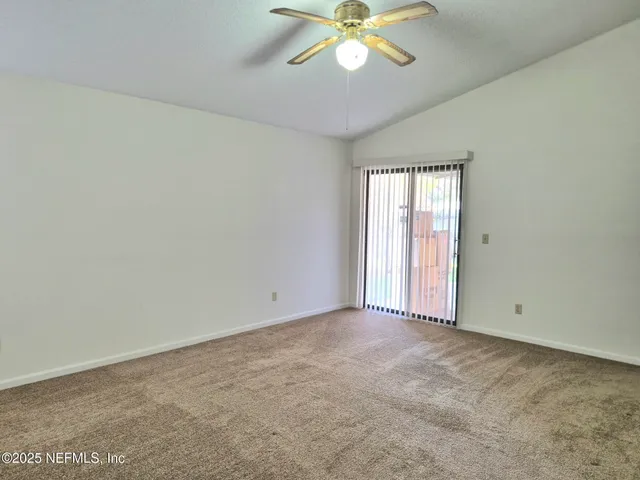 an empty room with a chandelier fan and windows