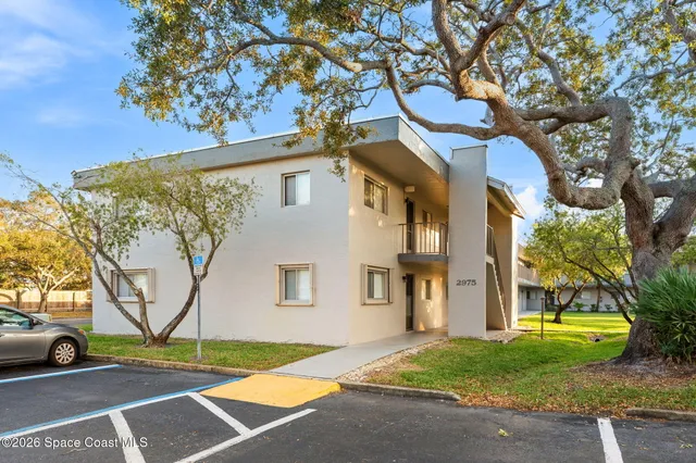 a view of a white house with a large tree