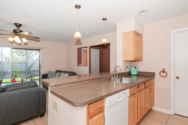 a kitchen with a sink a counter space and a view of living room