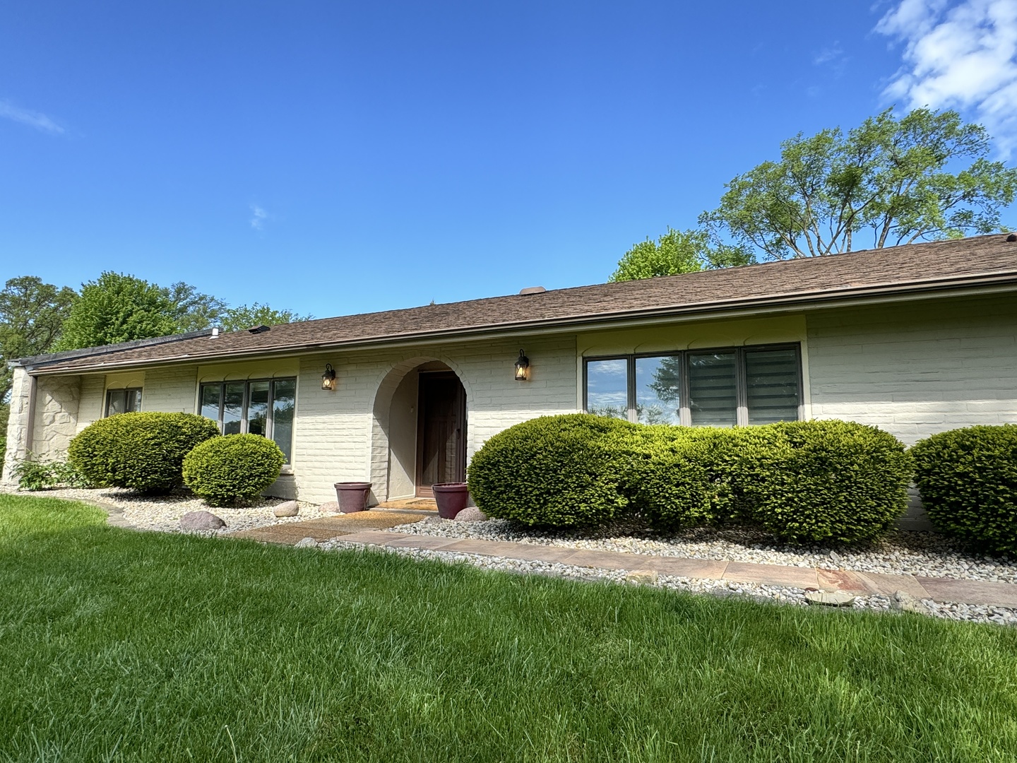 a front view of a house with a yard and potted plants